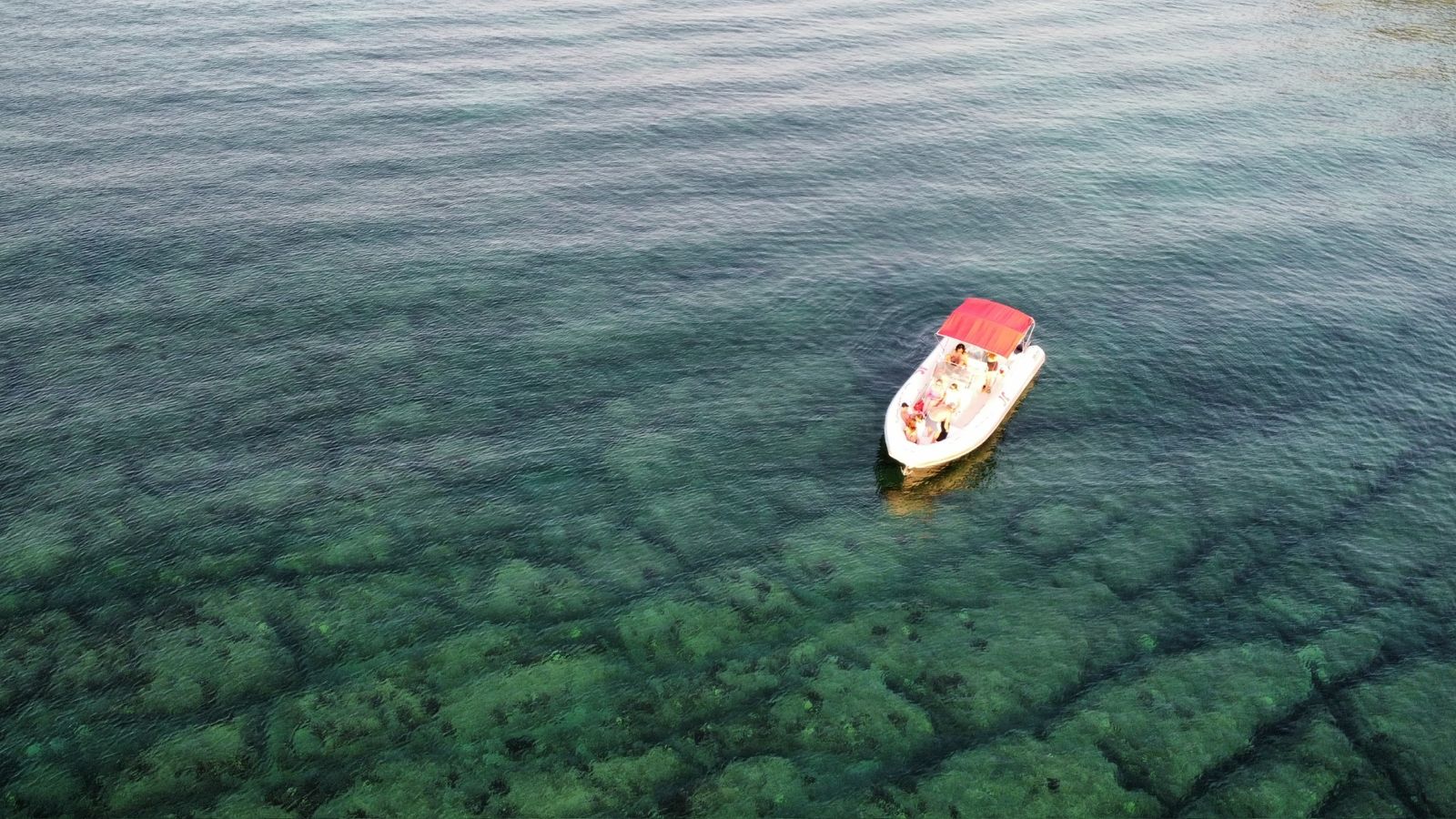 Barca elegante nella baia turchese di Ognina, costa rocciosa della Sicilia