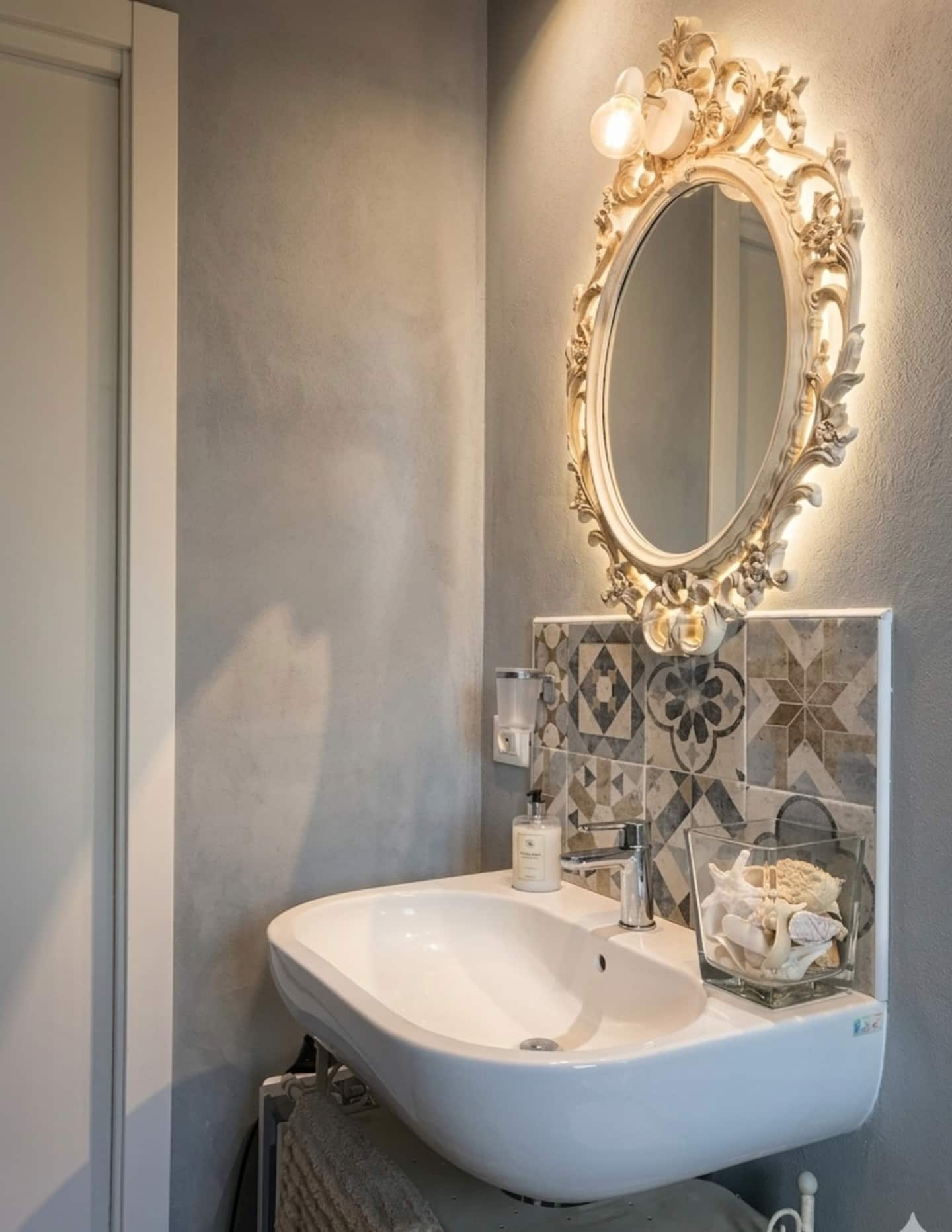 Dettaglio del bagno principale con specchio barocco e lavabo in ceramica